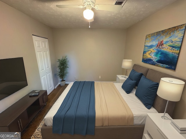 bedroom featuring a textured ceiling, a closet, dark hardwood / wood-style flooring, and ceiling fan