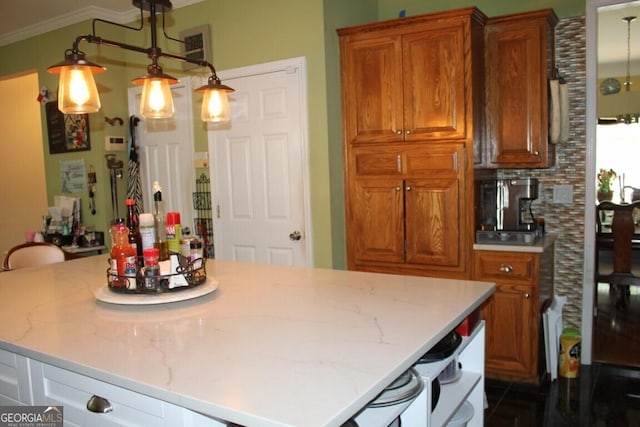 kitchen featuring decorative backsplash, light stone counters, ornamental molding, hanging light fixtures, and a breakfast bar area