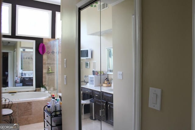 bathroom featuring tile patterned floors, tiled bath, and a healthy amount of sunlight