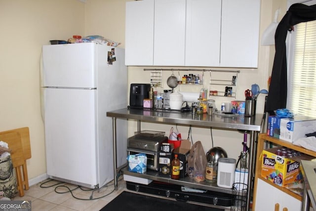 kitchen featuring white cabinetry, light tile patterned floors, stainless steel counters, and white refrigerator