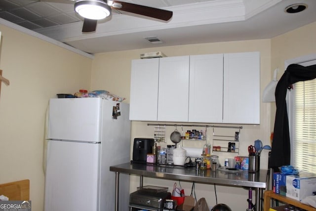 kitchen with stainless steel counters, crown molding, white cabinets, and white refrigerator