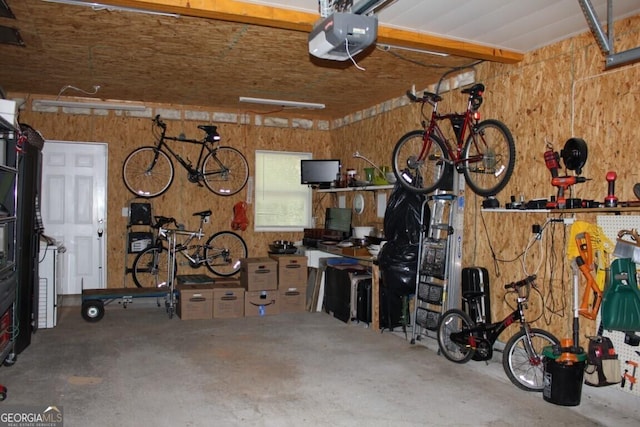 garage featuring a workshop area, wooden walls, and a garage door opener