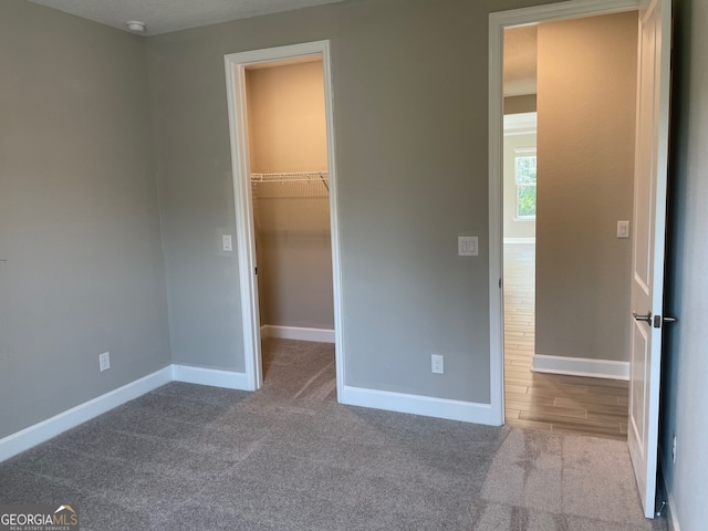 unfurnished bedroom featuring a spacious closet, a closet, carpet, and baseboards