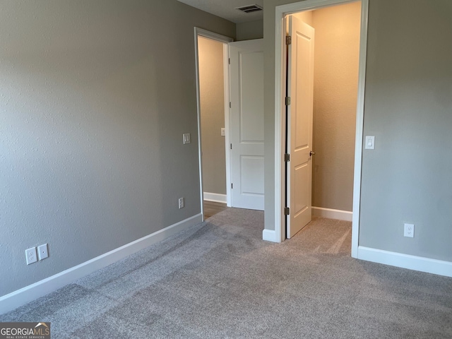 unfurnished bedroom with carpet flooring, visible vents, and baseboards