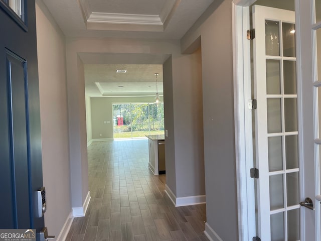 hall with dark wood-style floors, baseboards, a tray ceiling, and ornamental molding