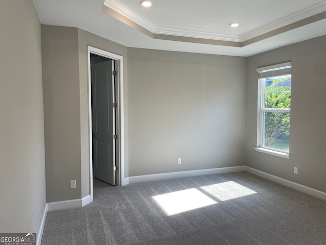 unfurnished room featuring ornamental molding, a raised ceiling, carpet flooring, and baseboards