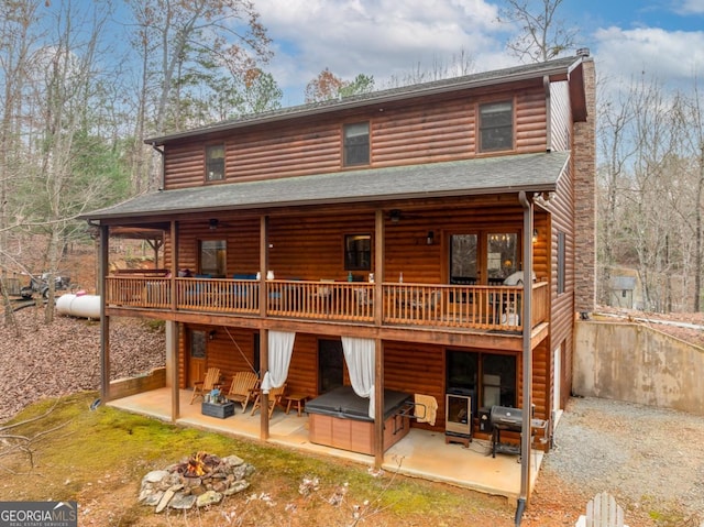 rear view of property with a wooden deck, a patio, and an outdoor fire pit