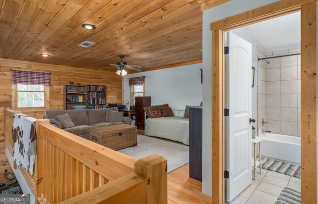 tiled living room featuring ceiling fan, wooden ceiling, and wooden walls