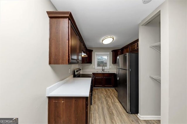 kitchen featuring stainless steel refrigerator, light hardwood / wood-style flooring, and dark brown cabinets