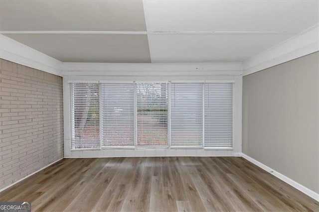 unfurnished room with wood-type flooring and brick wall