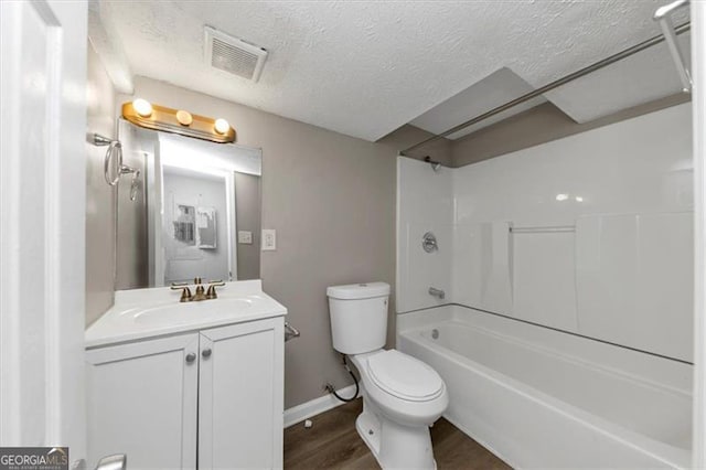 full bathroom featuring vanity, washtub / shower combination, toilet, a textured ceiling, and wood-type flooring