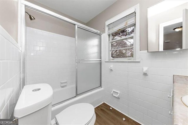 full bathroom with vanity, wood-type flooring, tile walls, enclosed tub / shower combo, and toilet