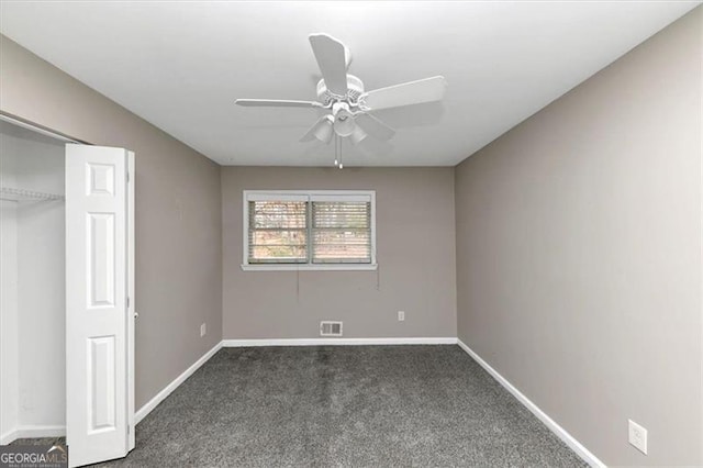 unfurnished bedroom featuring ceiling fan, dark carpet, and a closet