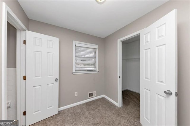 unfurnished bedroom featuring light colored carpet, a spacious closet, and a closet