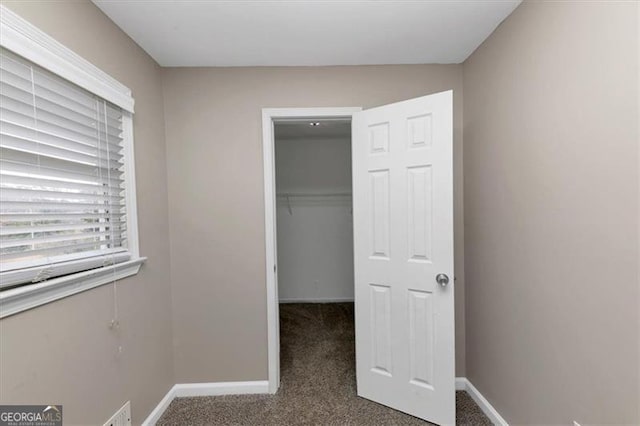 unfurnished bedroom featuring a walk in closet, carpet floors, and a closet