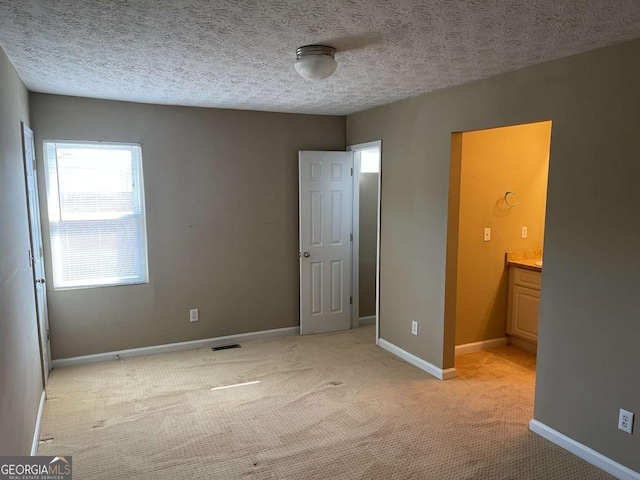 unfurnished bedroom with a textured ceiling and light carpet