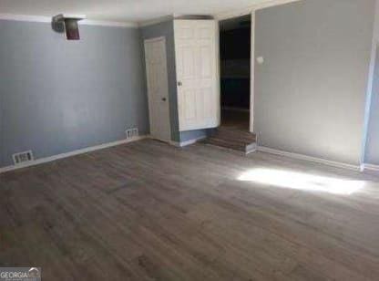 spare room with dark hardwood / wood-style flooring and crown molding