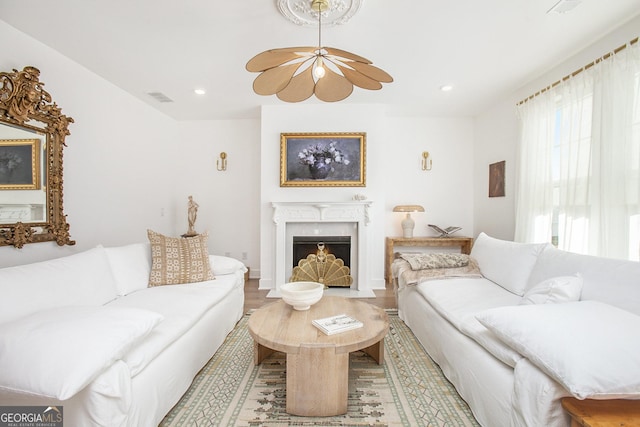 living room featuring a premium fireplace, hardwood / wood-style floors, and ceiling fan