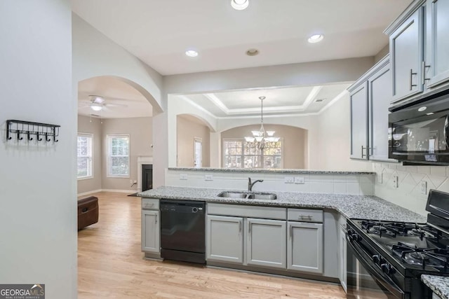 kitchen featuring gray cabinetry, black appliances, ceiling fan with notable chandelier, sink, and light stone countertops