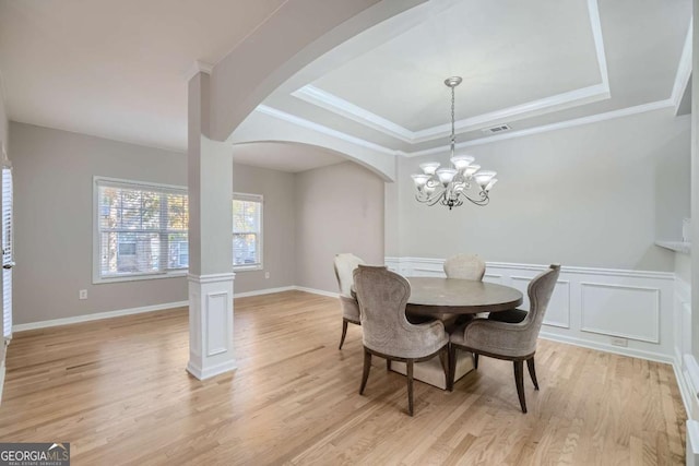 dining area with crown molding, light hardwood / wood-style flooring, and an inviting chandelier