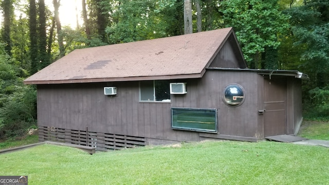 view of outdoor structure with a wall mounted air conditioner and a yard