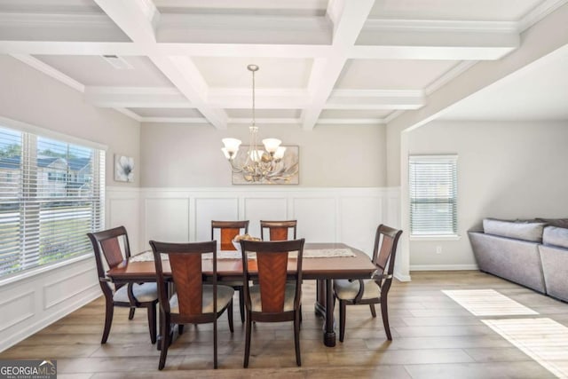 dining area featuring beam ceiling, wood-type flooring, crown molding, and a chandelier