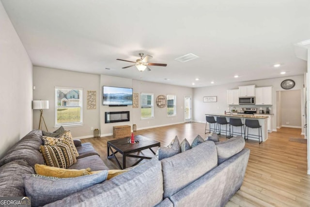 living room with light hardwood / wood-style floors, ceiling fan, and sink