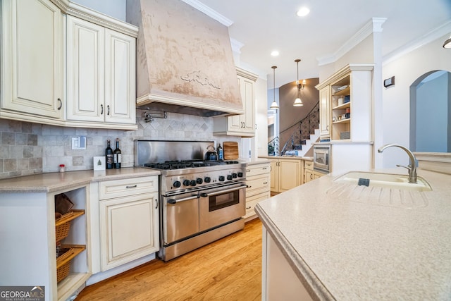 kitchen with premium range hood, sink, ornamental molding, pendant lighting, and stainless steel appliances