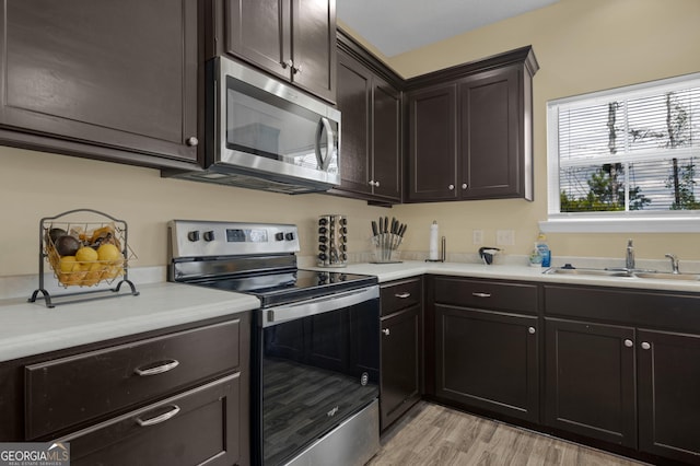 kitchen featuring dark brown cabinets, light hardwood / wood-style floors, sink, and appliances with stainless steel finishes