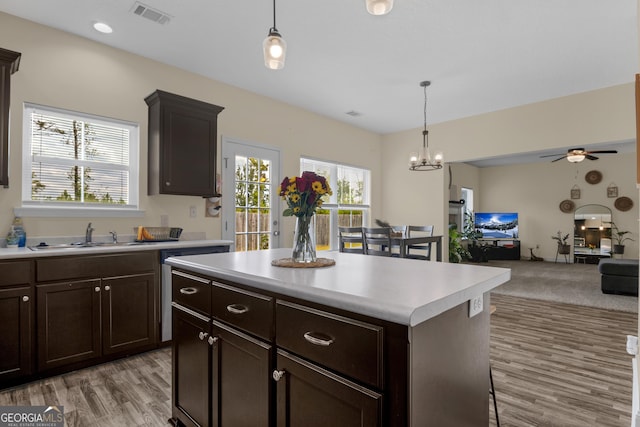 kitchen with sink, a center island, hanging light fixtures, light hardwood / wood-style flooring, and ceiling fan with notable chandelier