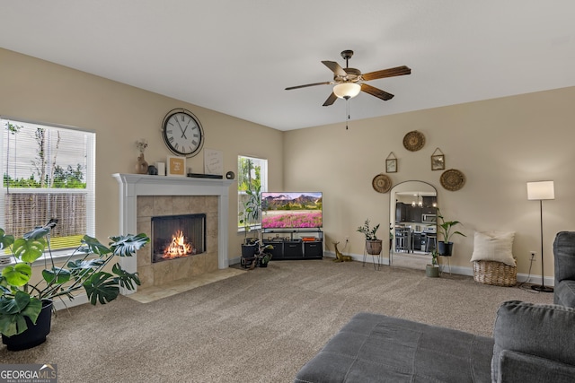 carpeted living room with a tile fireplace, a wealth of natural light, and ceiling fan