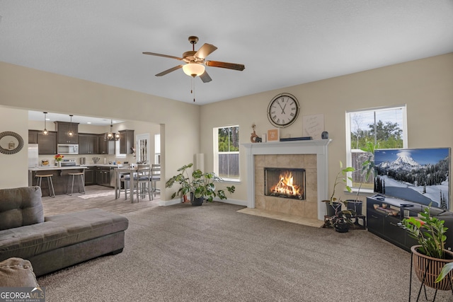 carpeted living room with ceiling fan and a fireplace