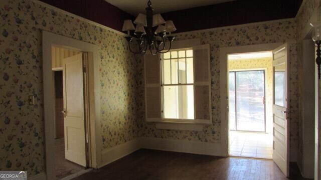 unfurnished dining area with hardwood / wood-style floors and an inviting chandelier