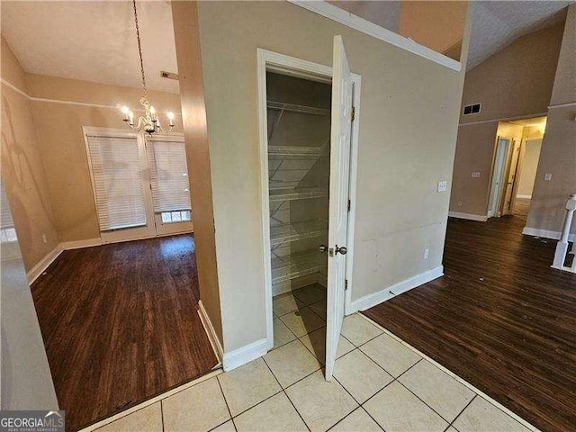 corridor featuring light tile patterned flooring, lofted ceiling, and an inviting chandelier