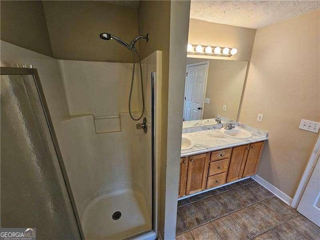 bathroom with vanity, a shower with shower door, and a textured ceiling