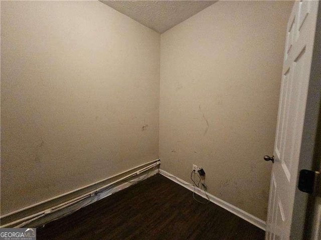 clothes washing area featuring hardwood / wood-style floors and a textured ceiling