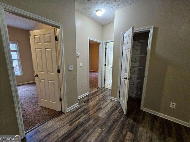 hall featuring a textured ceiling and dark wood-type flooring