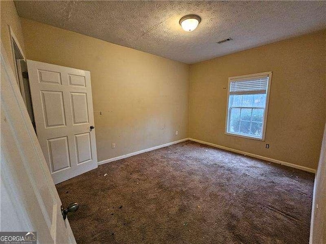 carpeted spare room featuring a textured ceiling