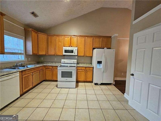 kitchen featuring a textured ceiling, sink, light tile patterned floors, and white appliances