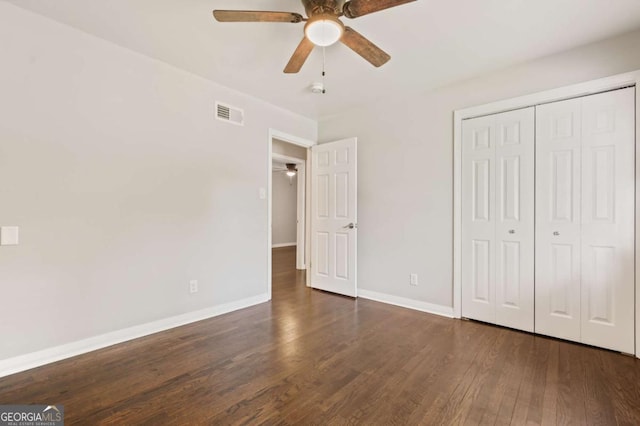 unfurnished bedroom with ceiling fan, a closet, and dark wood-type flooring