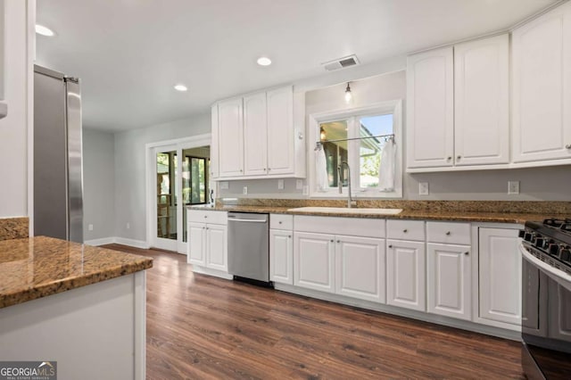 kitchen featuring dark stone countertops, sink, white cabinets, and appliances with stainless steel finishes