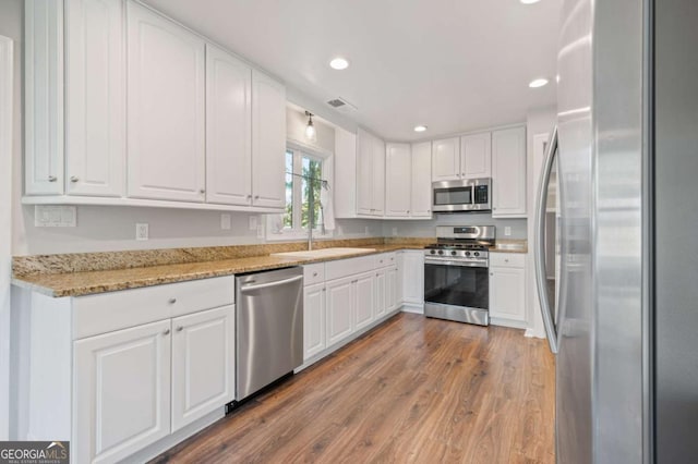 kitchen featuring white cabinets, light stone counters, sink, and stainless steel appliances