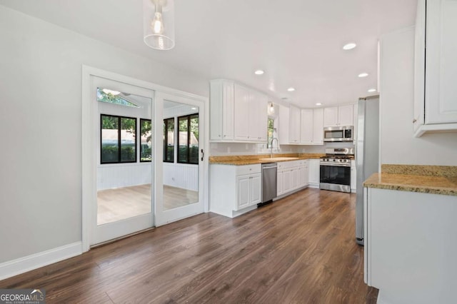 kitchen featuring white cabinets, sink, hanging light fixtures, dark hardwood / wood-style floors, and stainless steel appliances