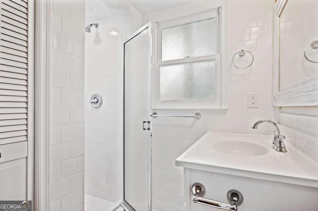 bathroom with decorative backsplash, a tile shower, and vanity