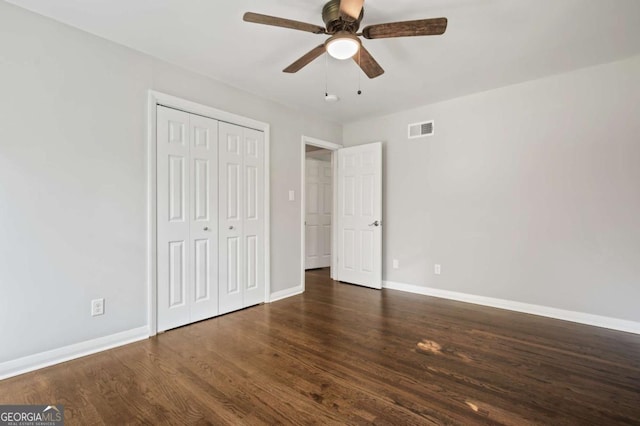 unfurnished bedroom with ceiling fan, a closet, and dark wood-type flooring