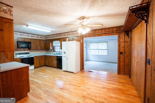 kitchen featuring ceiling fan, sink, light hardwood / wood-style flooring, a textured ceiling, and black appliances