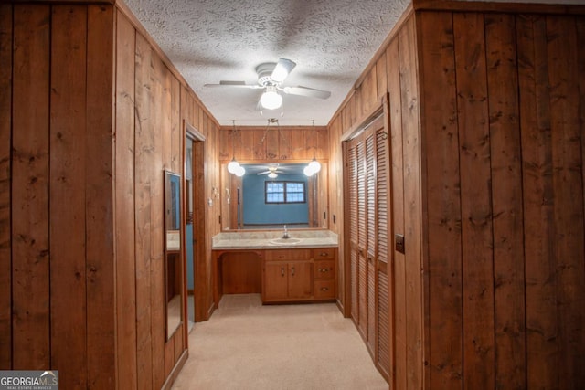 hall featuring sink, light colored carpet, crown molding, and wood walls