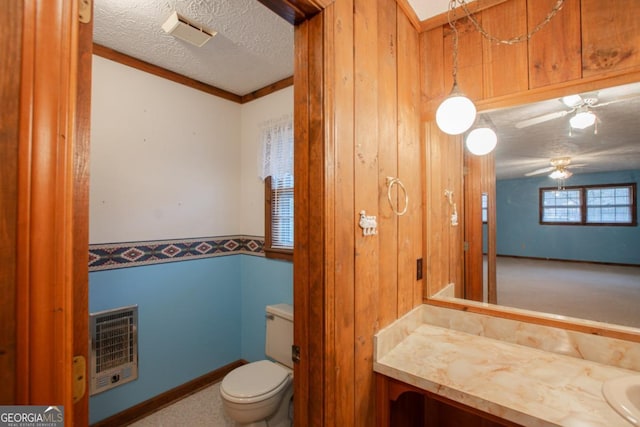 bathroom with ceiling fan, heating unit, a textured ceiling, toilet, and vanity