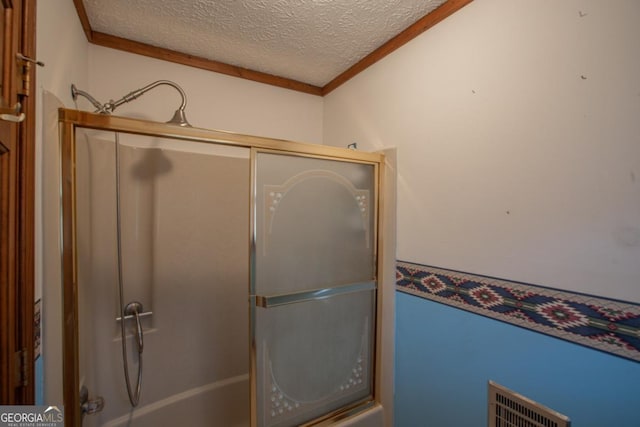 bathroom with crown molding, bath / shower combo with glass door, and a textured ceiling