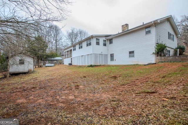 back of house with a storage shed